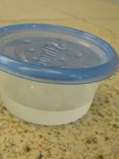 platic bowl lid with holes poked in it and vinegar inside bowl