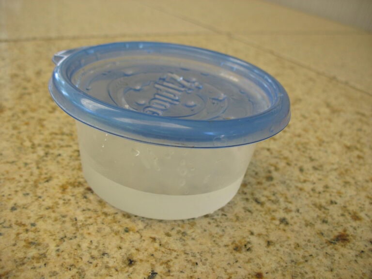 platic bowl lid with holes poked in it and vinegar inside bowl
