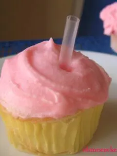 cupcake with pink frosting with straw in it