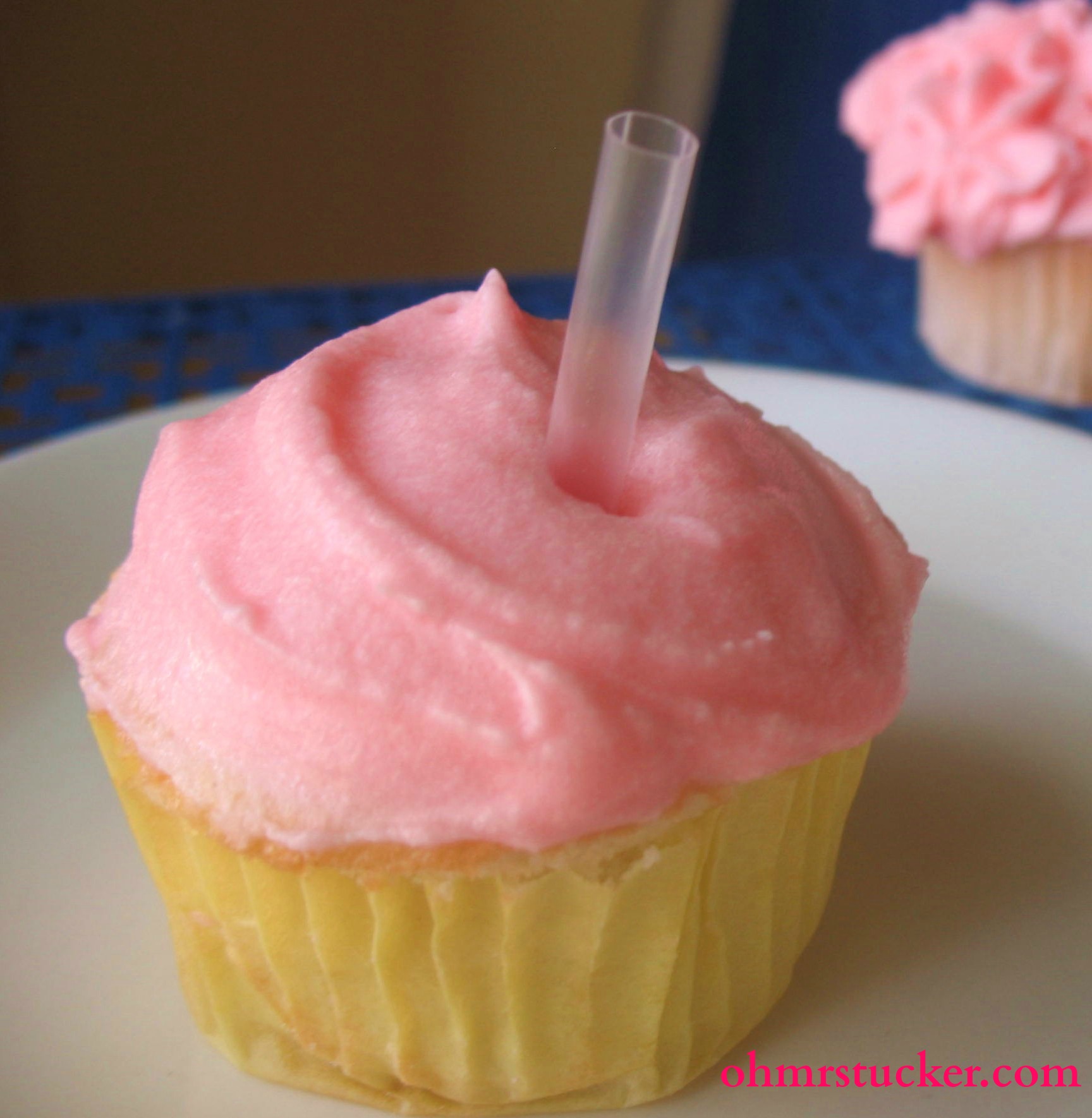 cupcake with pink frosting with straw in it