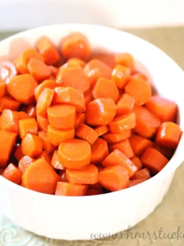Bright orange cooked carrots in a white bowl, perfect for healthy side dishes.