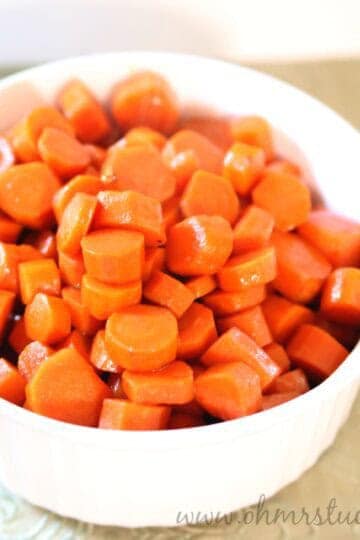 Bright orange cooked carrots in a white bowl, perfect for healthy side dishes.
