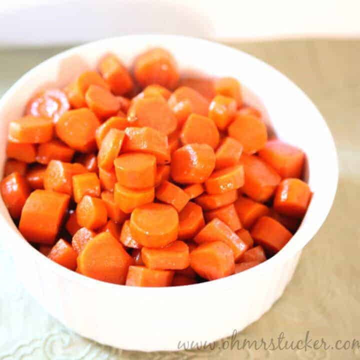 Bright orange cooked carrots in a white bowl, perfect for healthy side dishes.