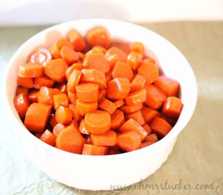 Bright orange cooked carrots in a white bowl, perfect for healthy side dishes.