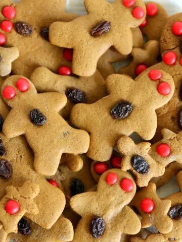 Gingerbread Men on a white plate on a table with a red holiday tablecloth