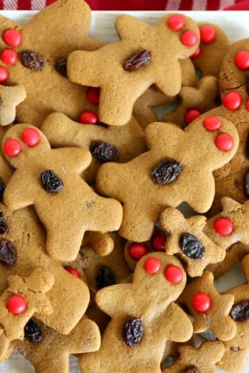 Gingerbread Men on a white plate on a table with a red holiday tablecloth
