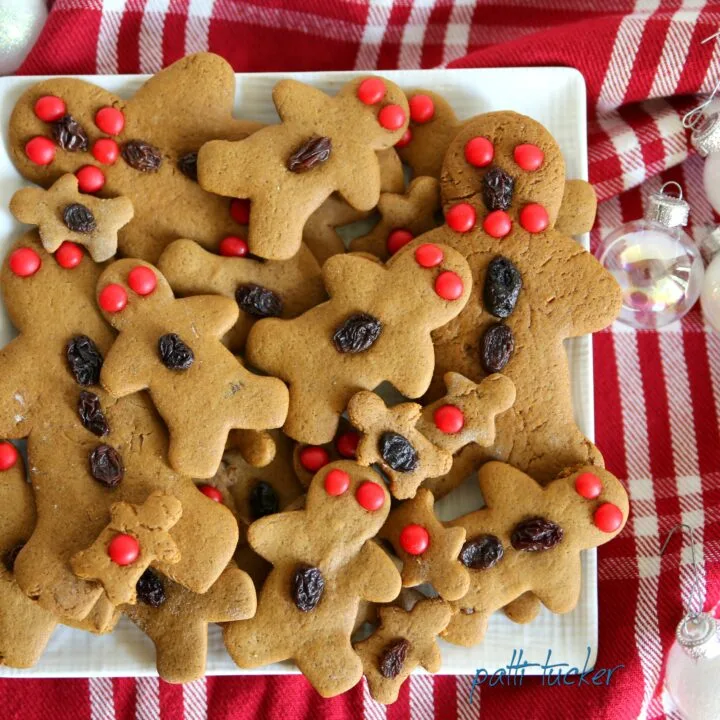 Gingerbread Men on a white plate on a table with a red holiday tablecloth