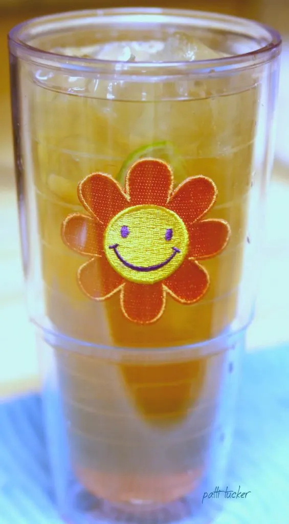 A glass of tea in a cup with a sun on it