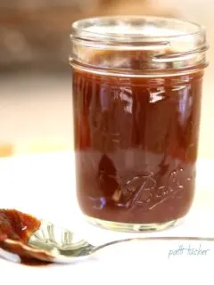 Slow Cooker Apple Butter in a jar with a spon beside it
