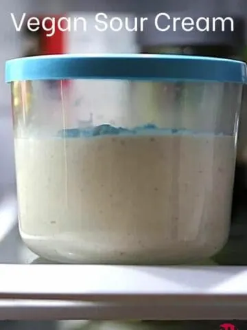 a glass dish with a blue lid with vegan sour cream in it