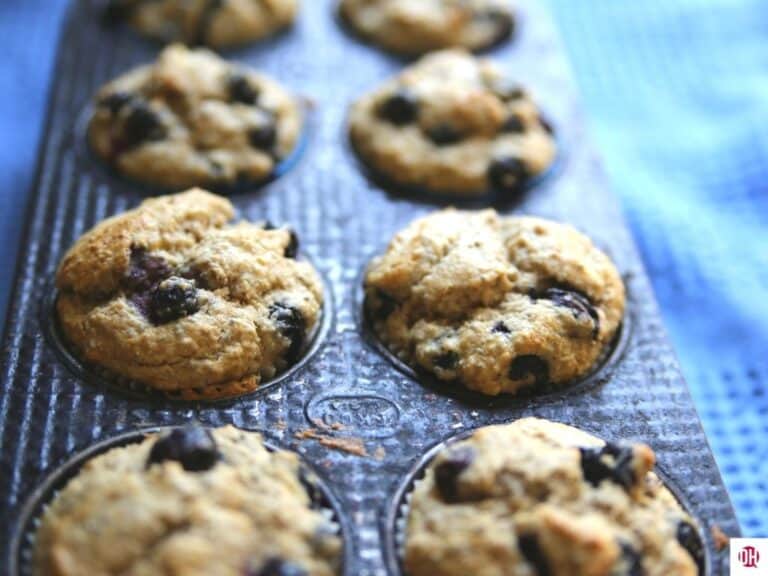 blueberry muffins still in tin on blue towel