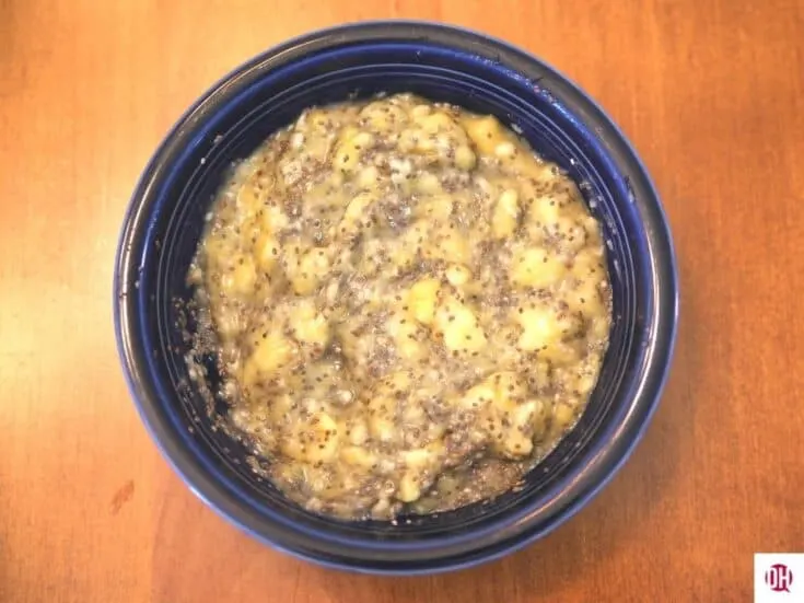 mashed banana and chia seeds mixed together in a blue bowl sitting on a table