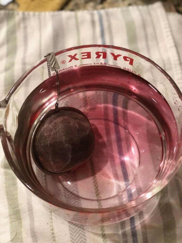 Measuring container with tea ball and hibiscus tea